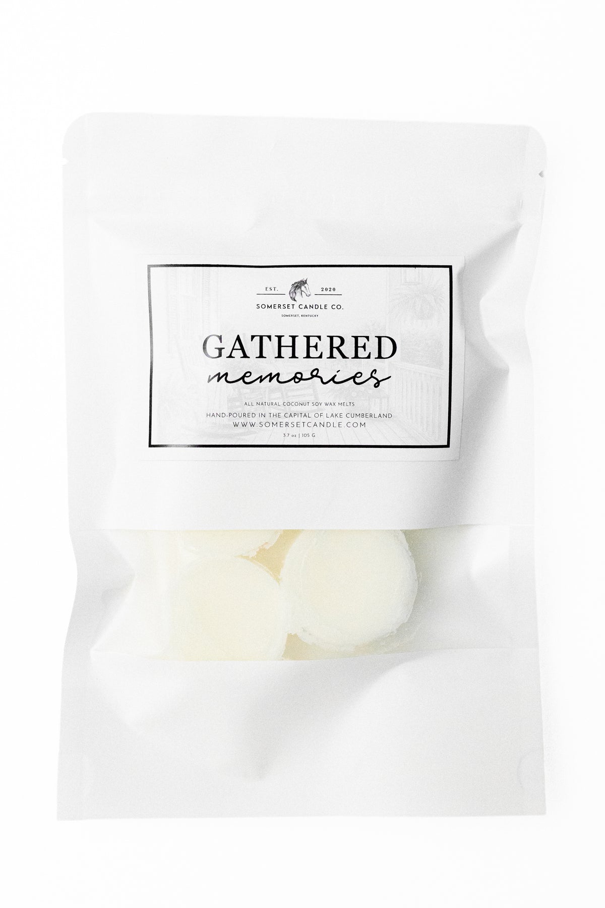 A white stand-up pouch package labeled 'Gathered Memories' with a clear lower section showing several round off-white wax melts inside, photographed on a white background.